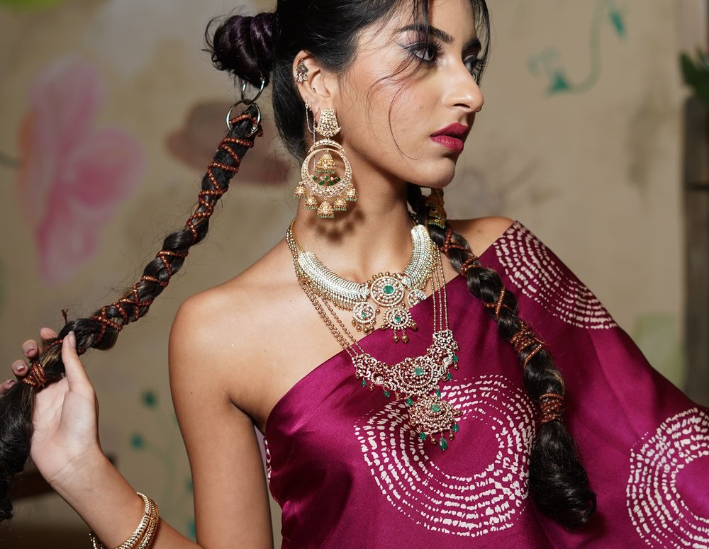 Model wearing a maroon printed saree with traditional Indian jewellery, representing the luxury craftsmanship curated by Ombre Showcase